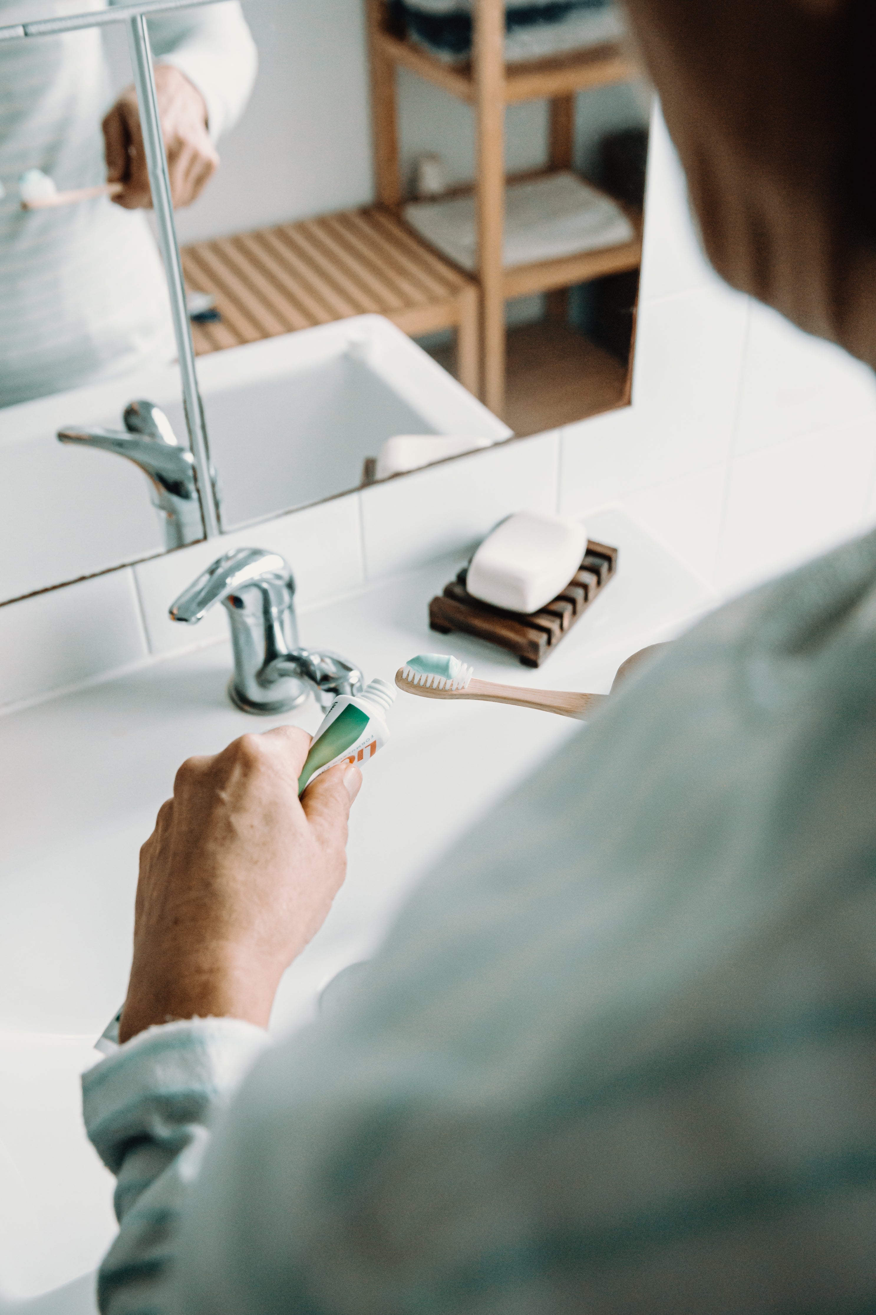 An older person brushing their teeth at the bathroom sink