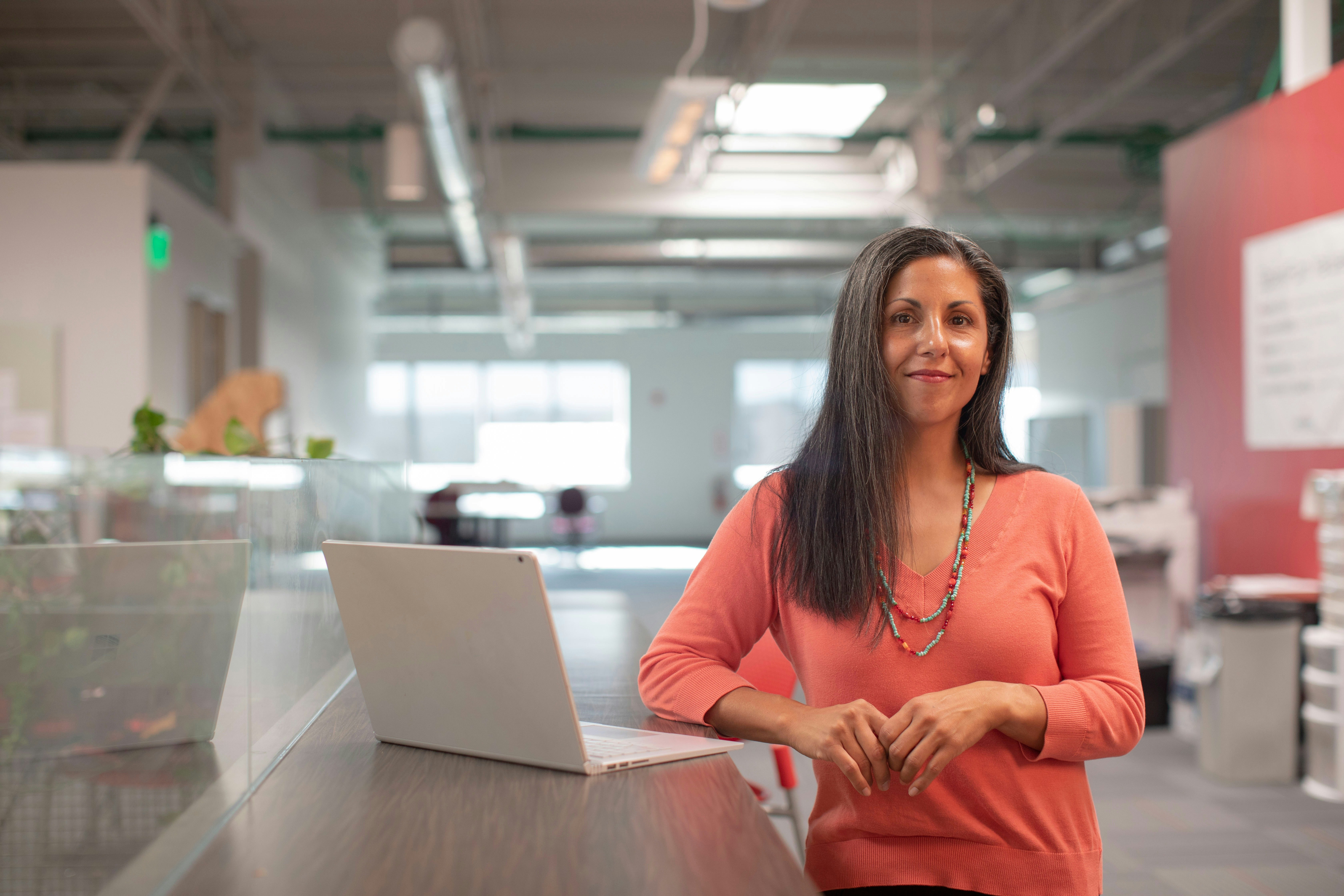 A smiling woman standing at her desk in an office