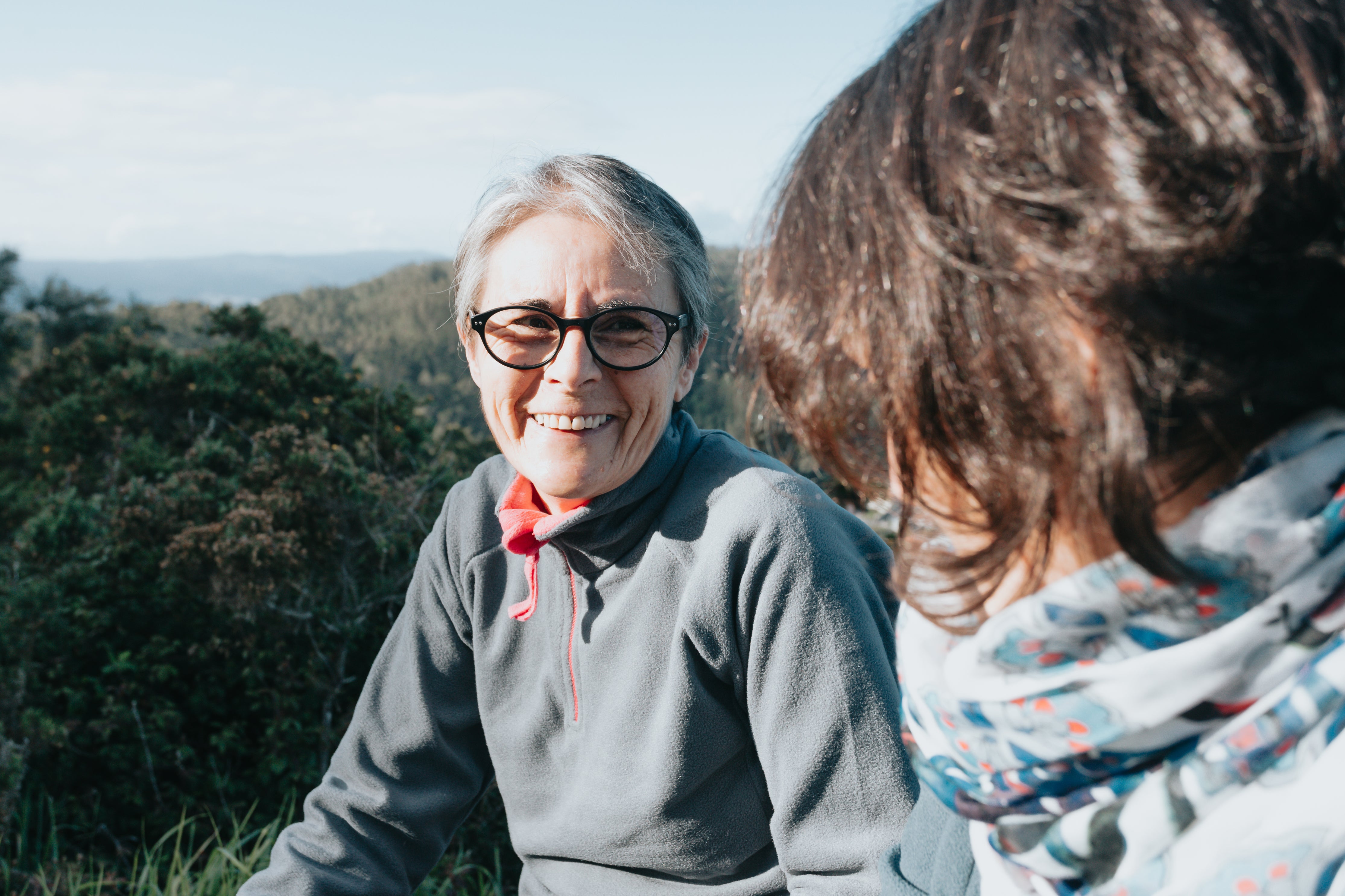 An older woman and a younger woman laughing together outdoors