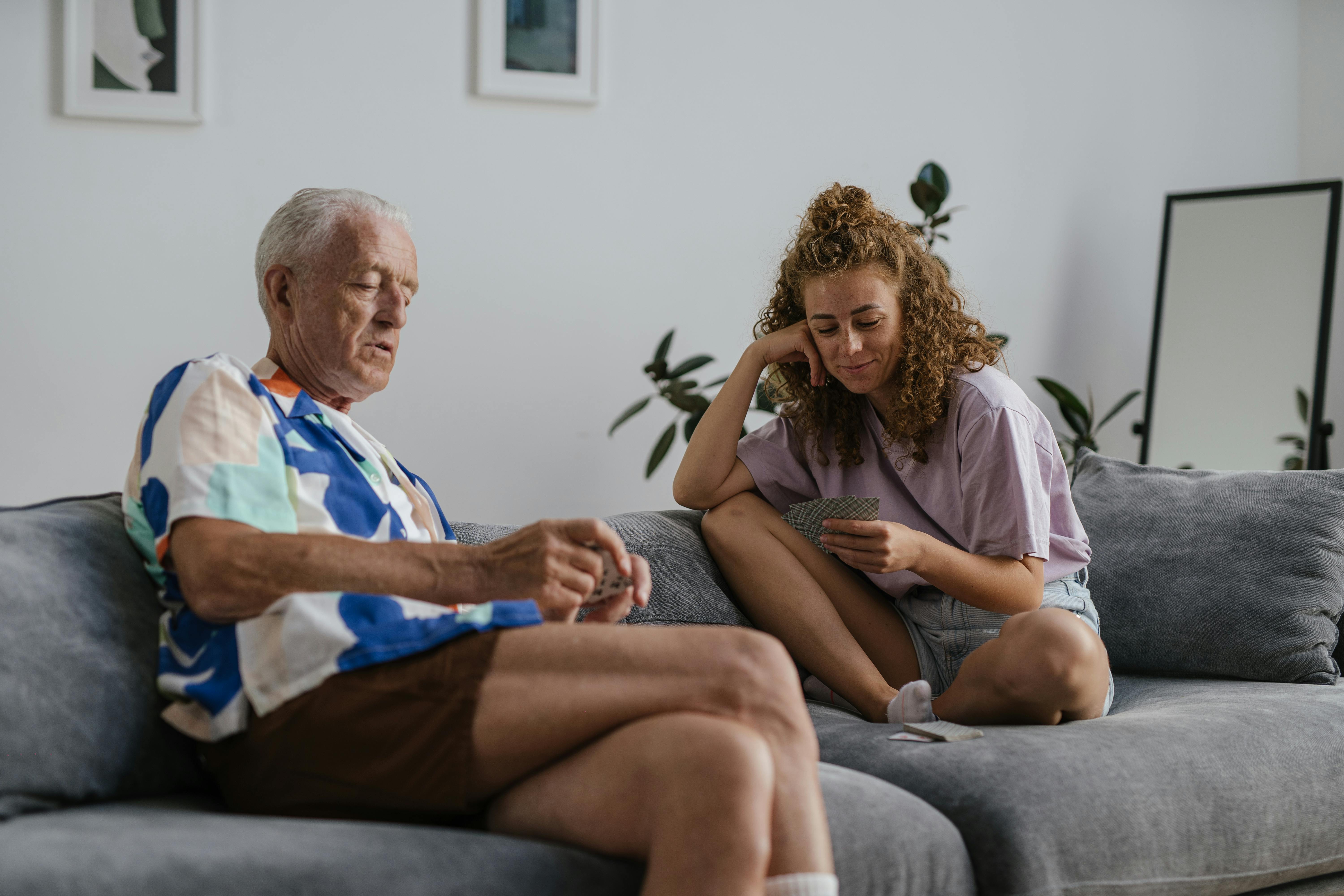 A caregiver and an older adult sitting together on a sofa